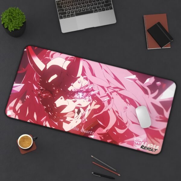A large gaming desk mat with Lilia Quartz in a dynamic battle pose, showing pink and blue crystal effects, set on a dark tabletop with a laptop, notebook, and coffee cup.