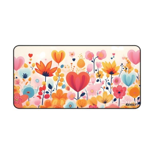 A flat lay of the beige floral desk mat with orange, red, and yellow flowers, set on a dark desk with coffee and pencils.
