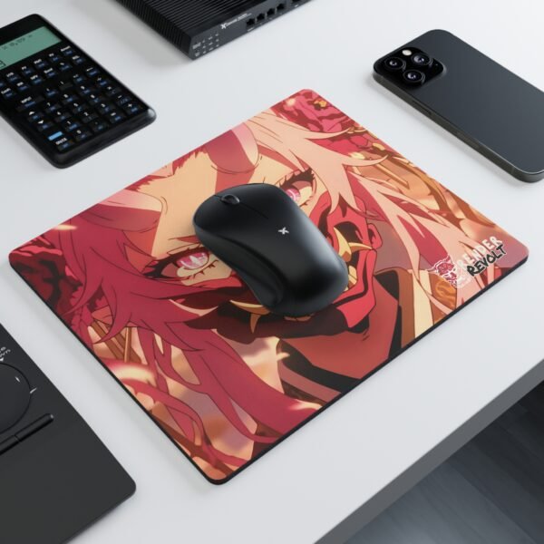 A modern workspace with a black wireless mouse resting on a vibrant anime-style mouse pad, featuring a striking character with long white-pink hair, intense pink eyes, and a red oni mask with sharp golden teeth.